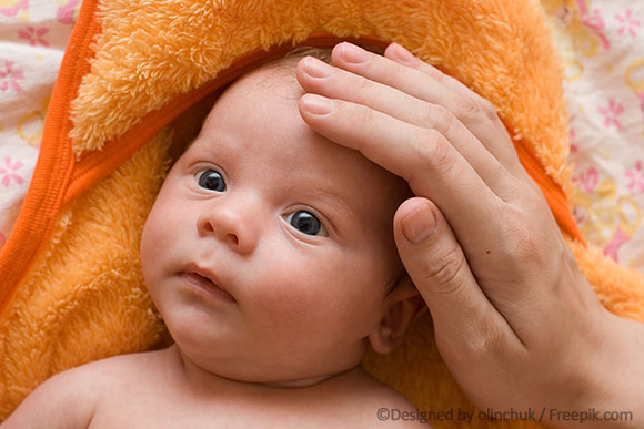 Baby mit Milchschorf wird gestreichelt am Kopf.
